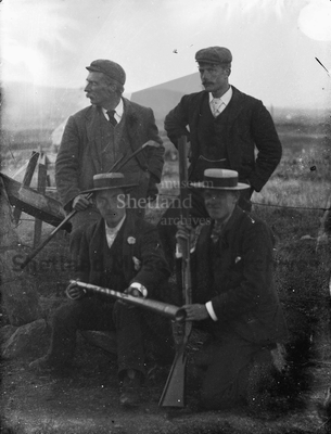 Group of four men, near a fence